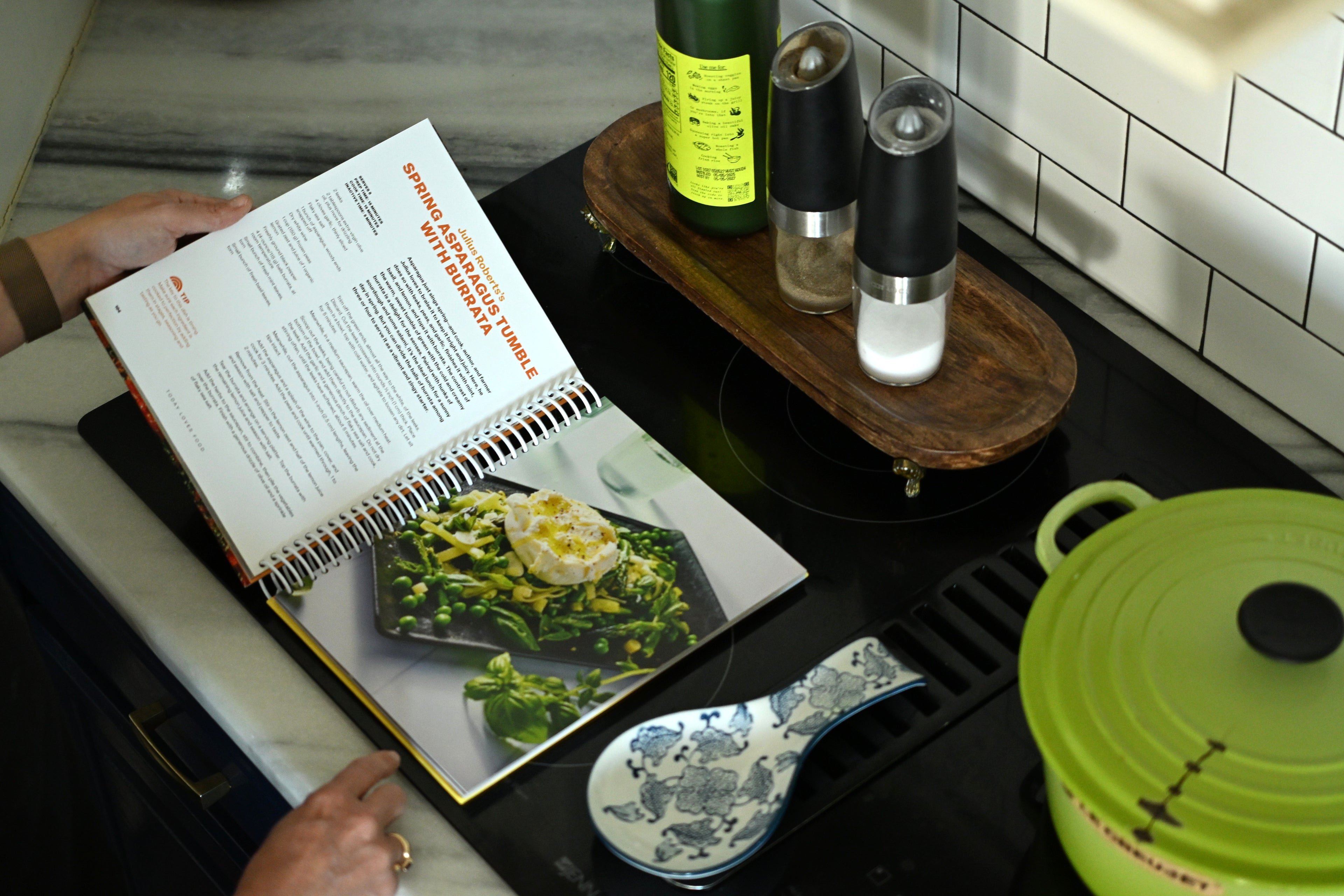 Person holding a spiral bound book with a recipe on it